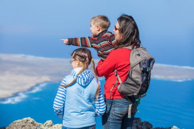 Mother and her child standing on cliff's edge clipart