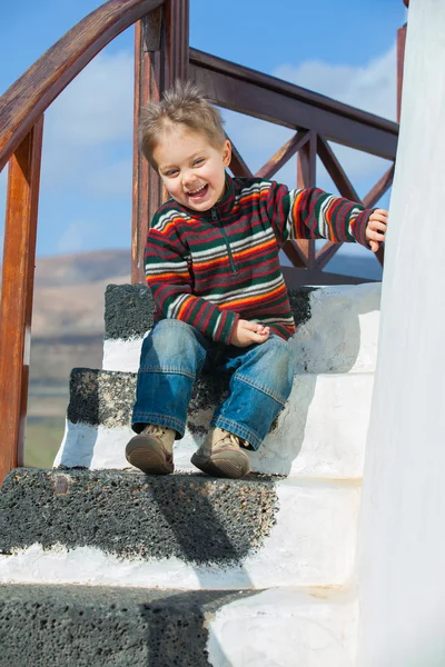Щасливий маленький хлопчик сидить на сходах — стокове фото