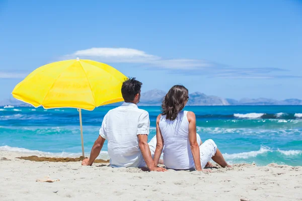 Пара сидящих вместе на пляже — стоковое фото