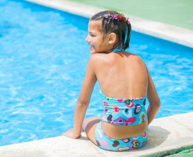 Pretty young girl at pool's edge clipart