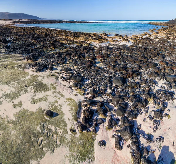 Beach with volcanic stones — Stock Photo, Image