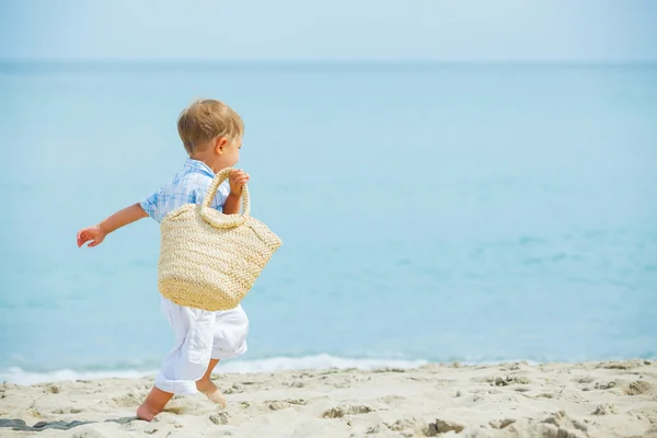Мальчик с сумкой на тропическом пляже — стоковое фото