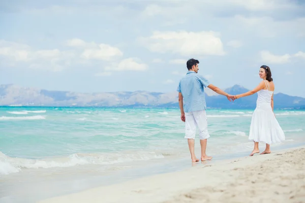 Lyckliga unga paret gå på en tropisk strand — Stockfoto