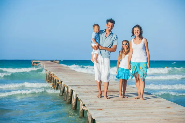 Family of four on jetty by the ocean — Stockfoto
