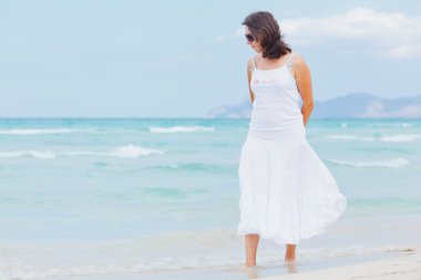 Young woman walking near blue sea.