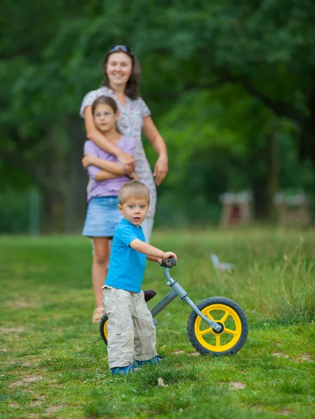 Little boy on a bicycle and his mother and sister — Stock Photo, Image