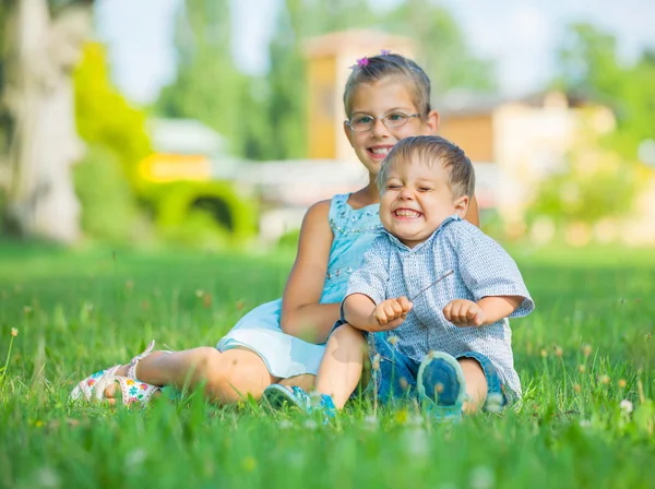 Liten pojke och hans syster i parken sommaren — Stockfoto
