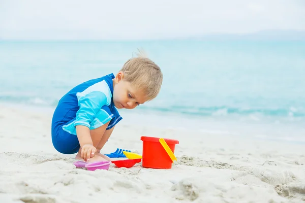 Menino brincando com brinquedos de praia na praia tropical — Fotografia de Stock