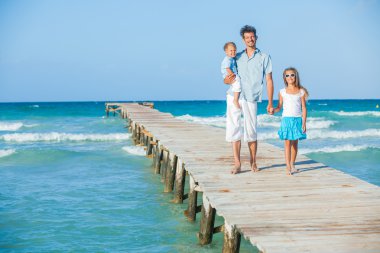 Family of three on jetty by the ocean clipart