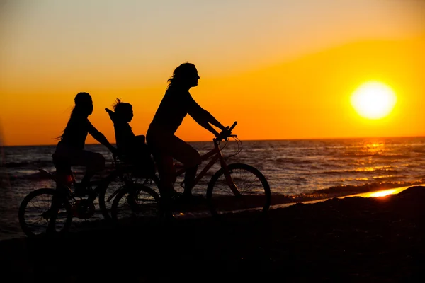 Mãe e seus filhos nas silhuetas de bicicleta — Fotografia de Stock