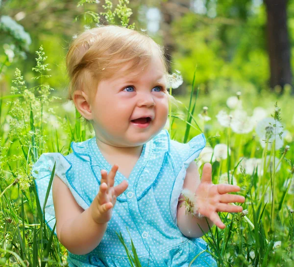 Malá dívka sedící v trávě v parku — Stock fotografie