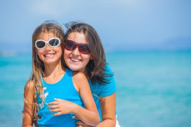 Mother and her daughter having fun on beach clipart