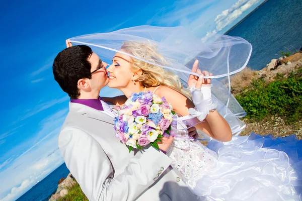Нежный поцелуй счастливого жениха и невесты на морском побережье — стоковое фото