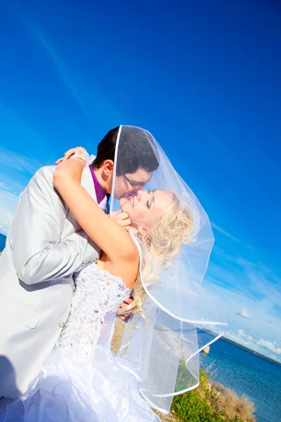 Ніжний поцілунок щасливого нареченого і нареченої на морському узбережжі — стокове фото