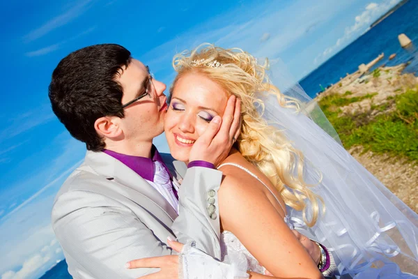 Τρυφερό φιλί του ευτυχής γαμπρού και της νύφης σε μια ακτή της θάλασσας — Φωτογραφία Αρχείου