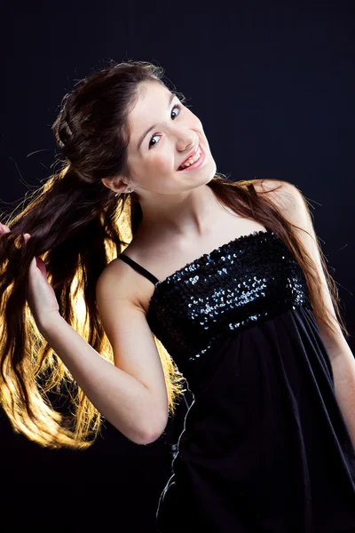 Teenager girl showing beautiful healthy long dark hair on black — Stock Photo, Image