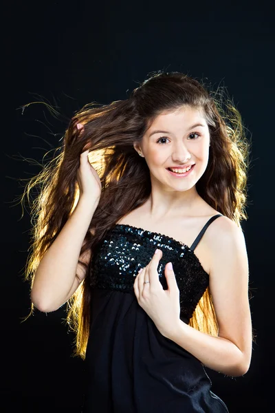 Девочка-подросток показывает красивые здоровые длинные темные волосы на черном — стоковое фото