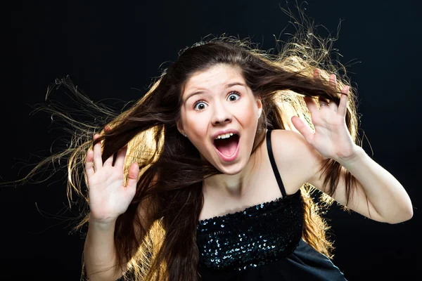 Roztomilá dívka s tmavými dlouhé vlasy křičí na černém pozadí — Stock fotografie