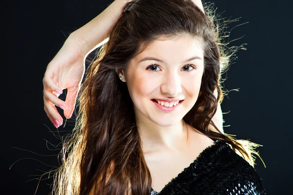 Roztomilé dospívající dívka s nádhernými dlouhými tmavými vlasy na černém pozadí — Stock fotografie