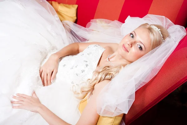 躺在红沙发上的美丽新娘 — 图库照片