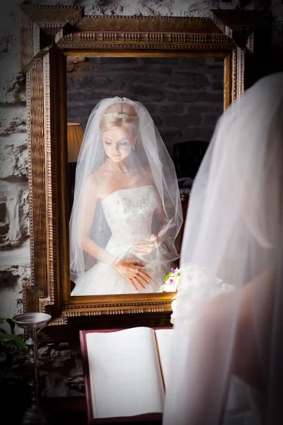 Красивая невеста в белом перед зеркалом — стоковое фото
