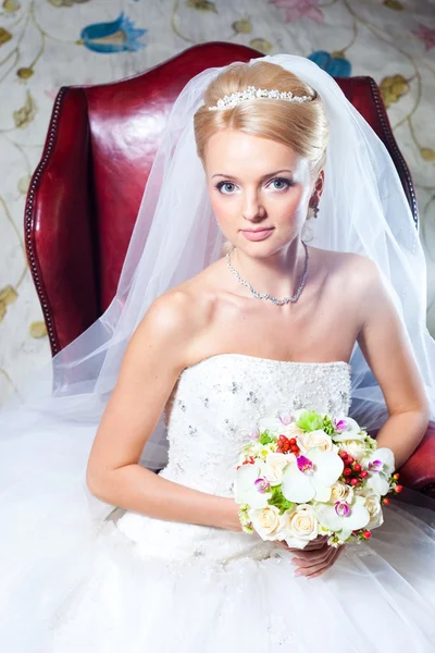 Beautiful bride sitting in red armchair — Stock Photo, Image