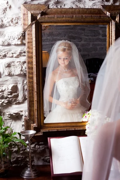 Mooie bruid in wit voor spiegel — Stockfoto