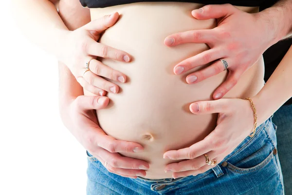 Mãos cuidadosas dos pais abraçando a barriga da mãe grávida — Fotografia de Stock