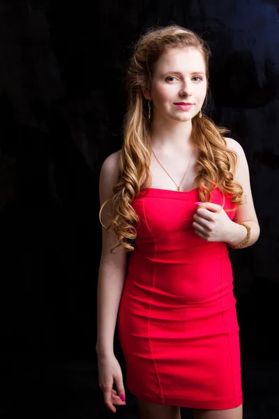 Aantrekkelijke jonge meisje dragen rode jurk op zwart — Stockfoto