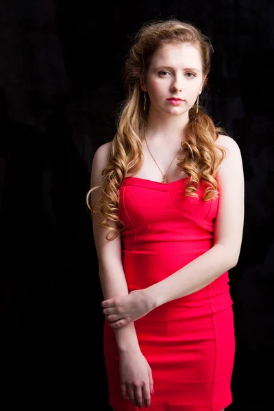 Attractive young girl wearing red dress on black — Stock Photo, Image