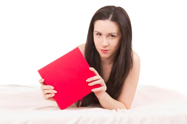 Красивая девушка с красным подарком лежит на белоснежной кровати — стоковое фото