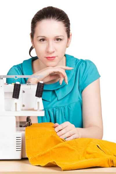 Девушка в синем платье на швейной машинке штопать — стоковое фото
