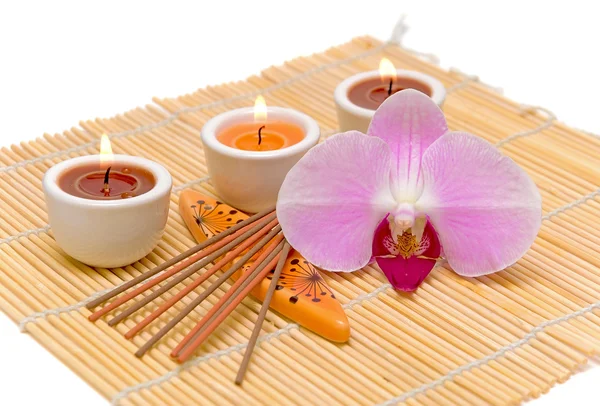 Concetto di centro benessere (candele, bastoncini di incenso e orchidea) su un dorso bianco — Foto Stock
