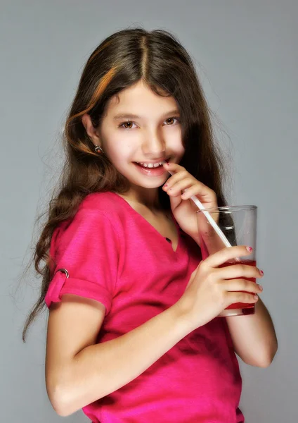 Ein Mädchen mit langen Haaren trinkt aus einer Tasse durch einen Schlauch. Stockfoto