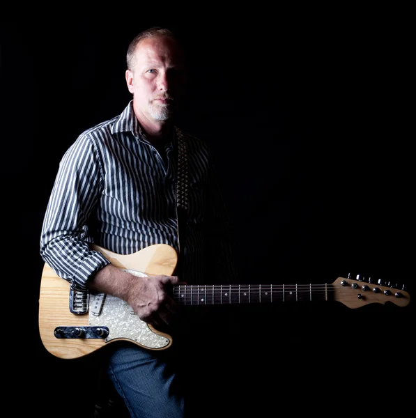 Заполненный тенью снимок крепкого на вид гитариста — стоковое фото