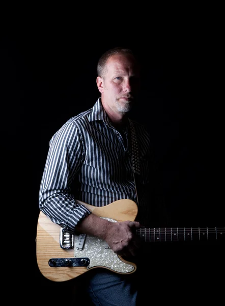 Заполненный тенью снимок крепкого на вид гитариста — стоковое фото