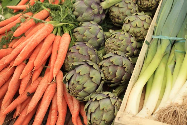 Puerros zanahorias alcachofas en primavera en un mercado — Foto de Stock