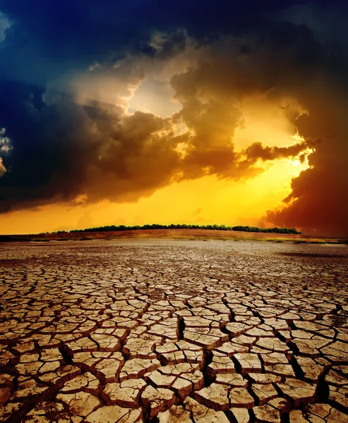 Pôr-do-sol dramático sobre terra seca rachada — Fotografia de Stock
