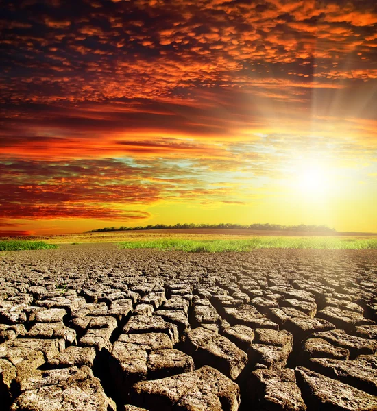 Tierra de sequía con nubes rojas y puesta del sol — Foto de Stock