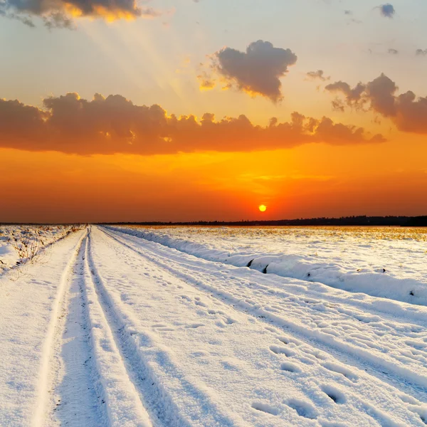 Röd solnedgång över vägen med snö — Stockfoto