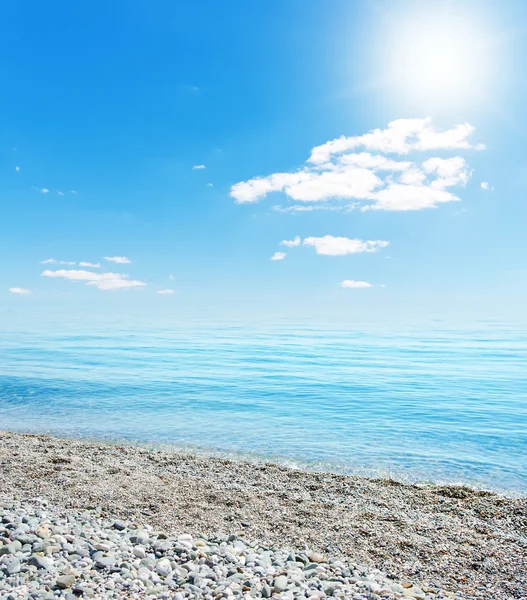 Солнце над пляжем с камнями — стоковое фото