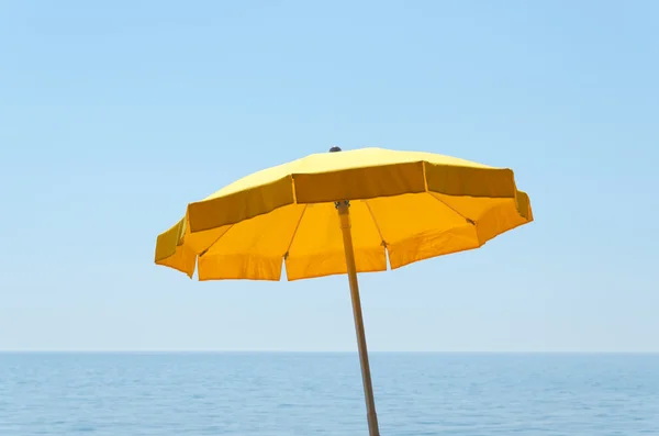 Guarda-chuva amarelo sobre o mar sob o céu azul — Fotografia de Stock