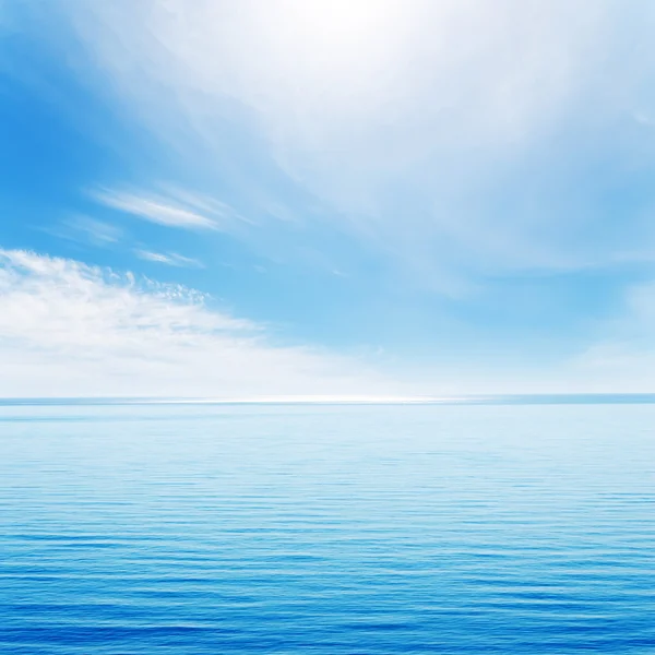 Vagues claires sur la mer bleue et ciel nuageux avec soleil — Photo