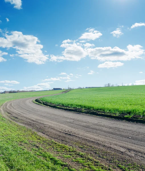 Kronkelende landelijke weg onder blauw bewolkte hemel — Stockfoto
