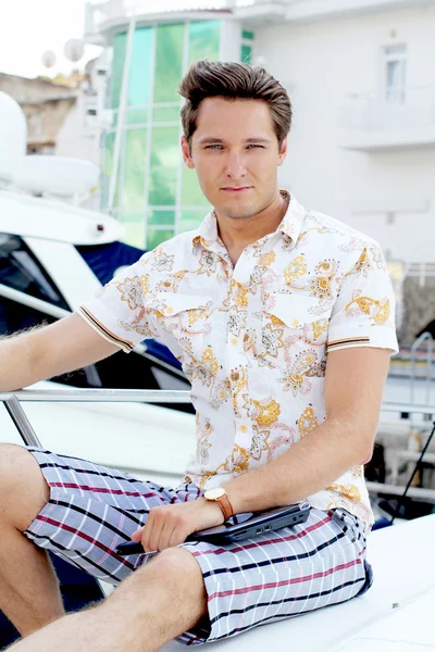 Handsome man with laptop sitting on white yacht — Stock Photo, Image