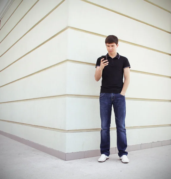Handsome student using a mobile phone with perspective wall copyspace — Stock Photo, Image