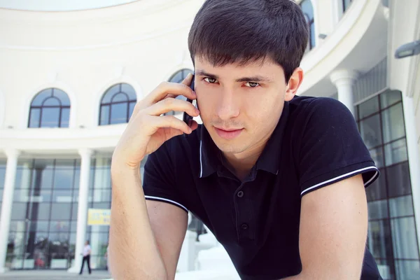 Schöner junger Mann, der ein Handy mit Kopierplatz benutzt — Stockfoto