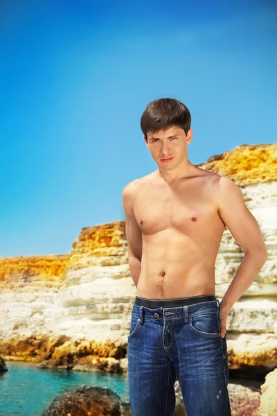 Portrét sexy mladík hodí na pláž, modrá obloha — Stock fotografie