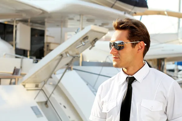 Красивый мужчина, серьезный капитан в белой рубашке рядом с яхтой , — стоковое фото
