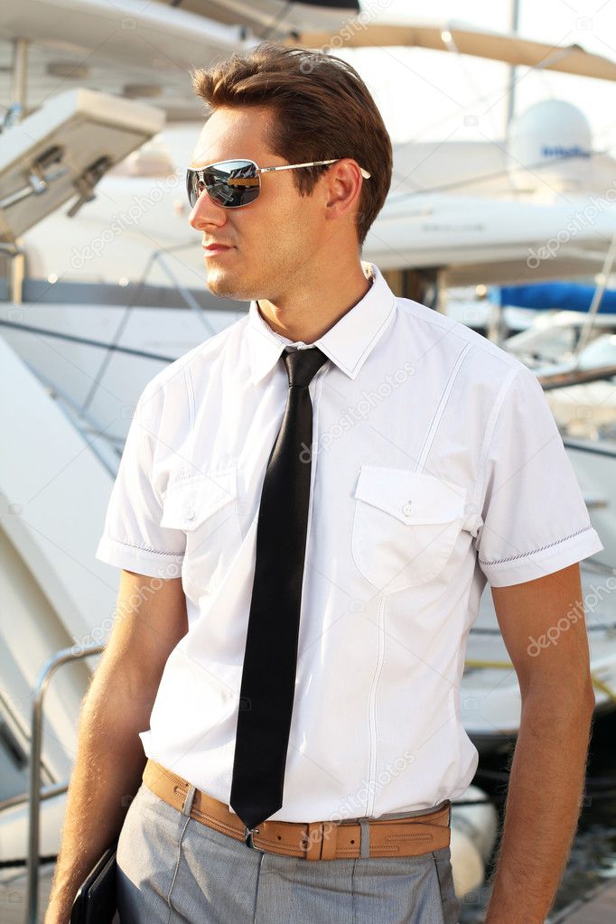 Man captain in a white shirt near the yacht, looking away